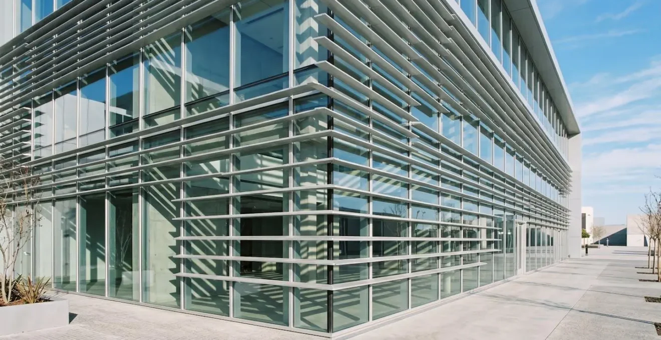 Façade vitrée moderne avec brise-soleil orientables protégeant du rayonnement direct